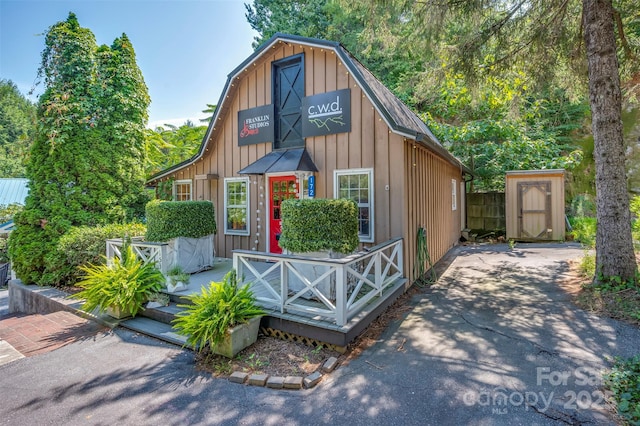 view of front of home with board and batten siding, fence, and a gambrel roof