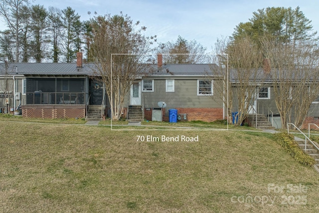 back of property featuring entry steps, a sunroom, a lawn, and a chimney