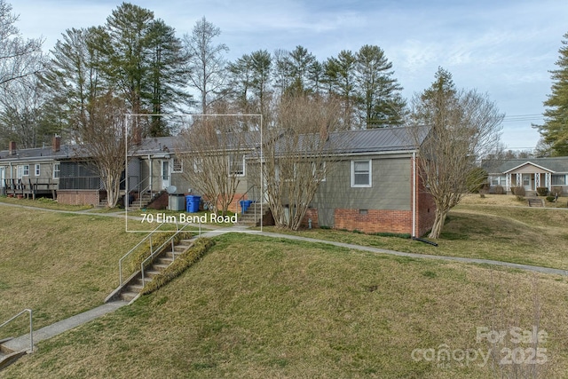 back of property featuring entry steps, crawl space, a lawn, and metal roof