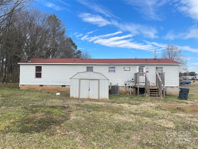 back of property featuring a lawn, crawl space, a shed, cooling unit, and an outdoor structure