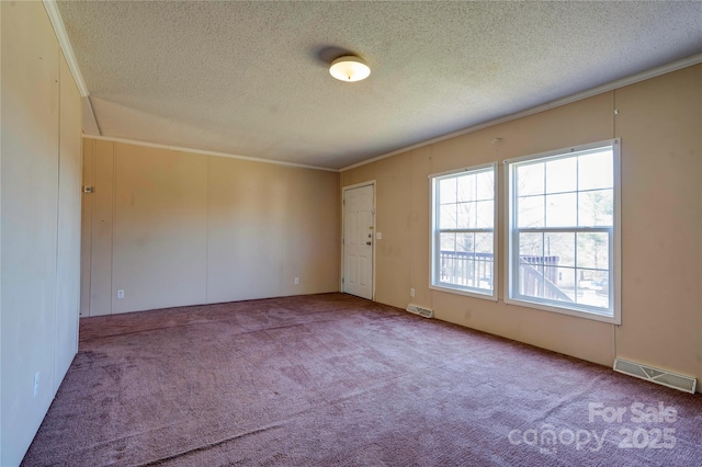 empty room with a textured ceiling, carpet floors, ornamental molding, and visible vents