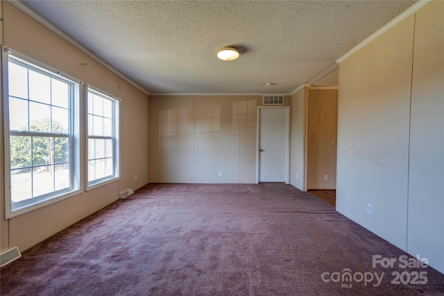 carpeted spare room with a textured ceiling, ornamental molding, and visible vents