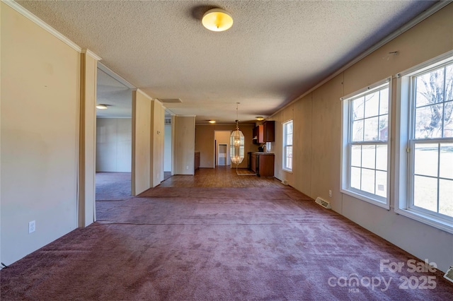 unfurnished living room featuring a textured ceiling, carpet floors, visible vents, and crown molding