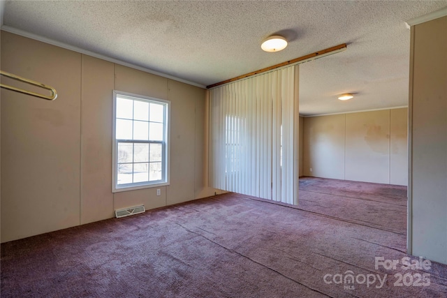 carpeted spare room with visible vents and a textured ceiling