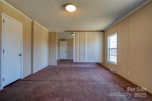 carpeted spare room featuring a textured ceiling, visible vents, and crown molding