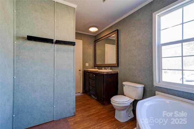 full bathroom with toilet, wood finished floors, a textured ceiling, vanity, and a bath