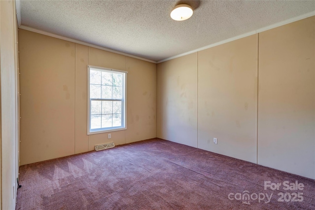 carpeted spare room with visible vents, a textured ceiling, and ornamental molding