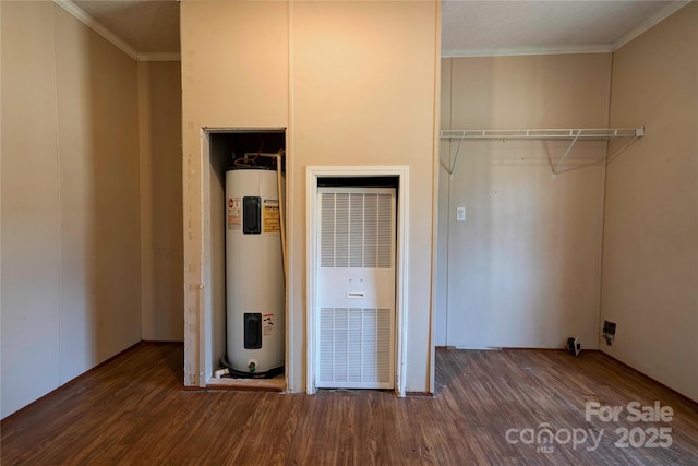 laundry room featuring dark wood-type flooring, a heating unit, electric water heater, and ornamental molding