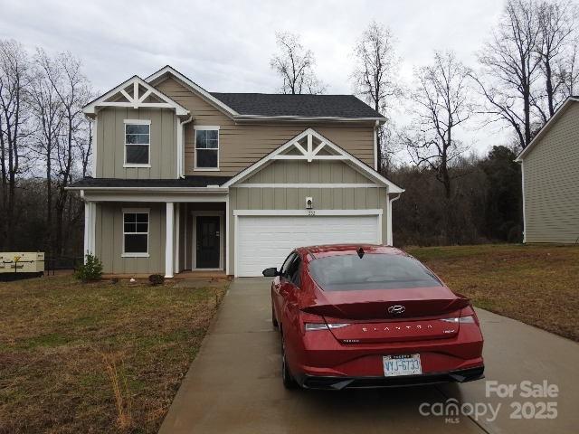 view of front of property with a garage, concrete driveway, a front lawn, and board and batten siding