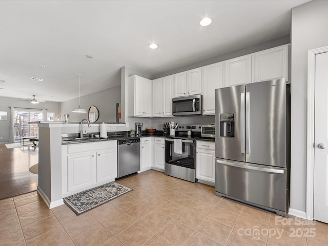 kitchen featuring a peninsula, appliances with stainless steel finishes, a sink, and white cabinets