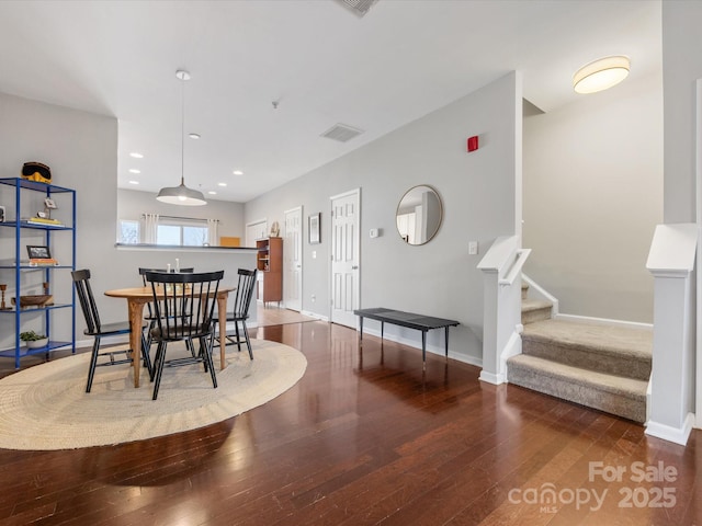 dining area with stairs, hardwood / wood-style floors, visible vents, and baseboards