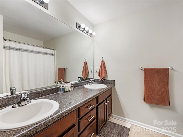 bathroom with tile patterned flooring, a sink, baseboards, and double vanity