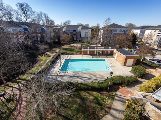 community pool with a patio area, a residential view, and fence