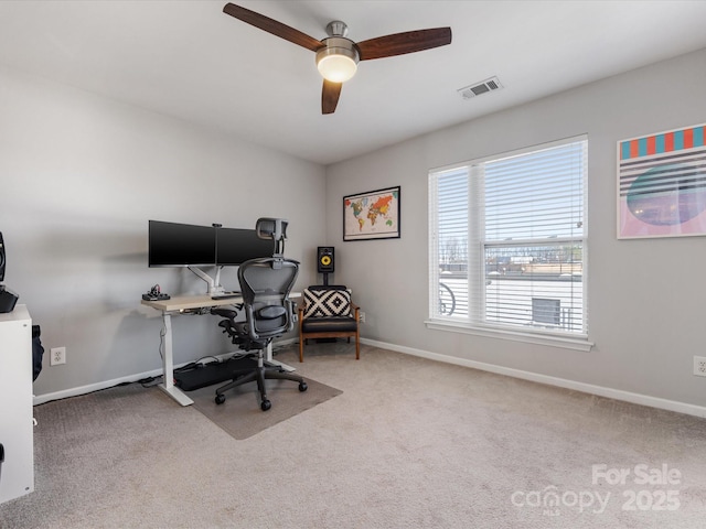 carpeted home office featuring a ceiling fan, visible vents, and baseboards