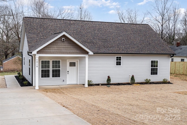 view of front facade with a shingled roof and fence