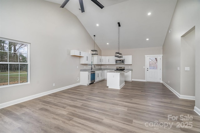 kitchen with stainless steel appliances, light countertops, white cabinetry, wood finished floors, and baseboards