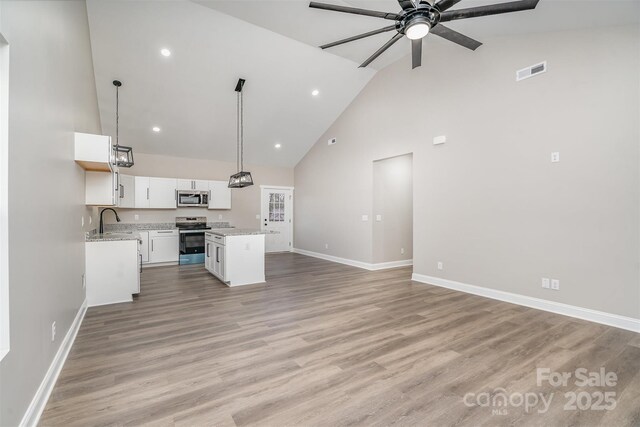 kitchen featuring visible vents, appliances with stainless steel finishes, open floor plan, a center island, and a sink