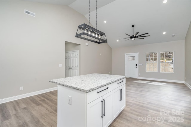 kitchen with open floor plan, baseboards, a kitchen island, and light wood finished floors