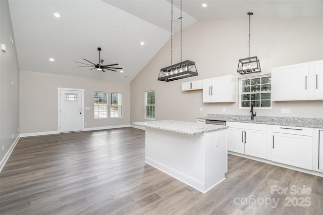 kitchen featuring light stone counters, light wood finished floors, white cabinets, and a center island