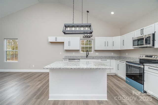 kitchen featuring high vaulted ceiling, appliances with stainless steel finishes, a sink, and a center island