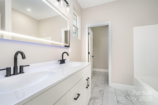 bathroom with marble finish floor, double vanity, a sink, and baseboards