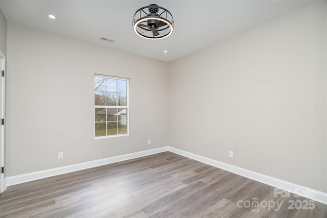 unfurnished room with recessed lighting, wood finished floors, visible vents, and baseboards