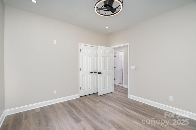 interior space with baseboards, wood finished floors, and recessed lighting