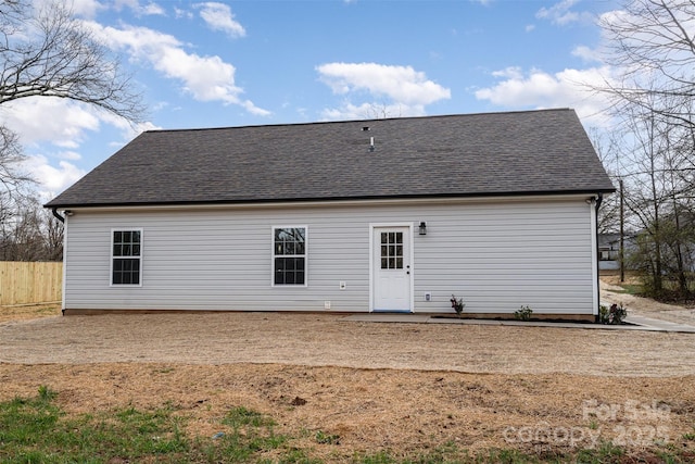 rear view of property with roof with shingles and fence