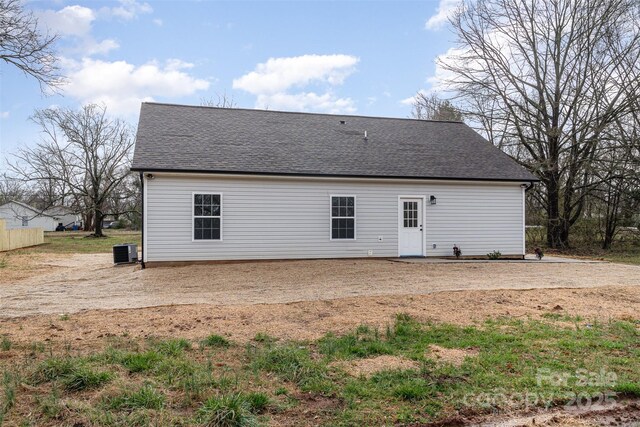 back of property featuring central AC and a shingled roof