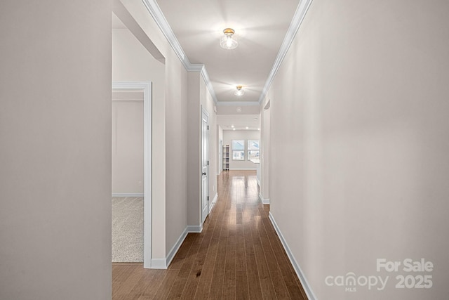 hall featuring crown molding, baseboards, and wood finished floors