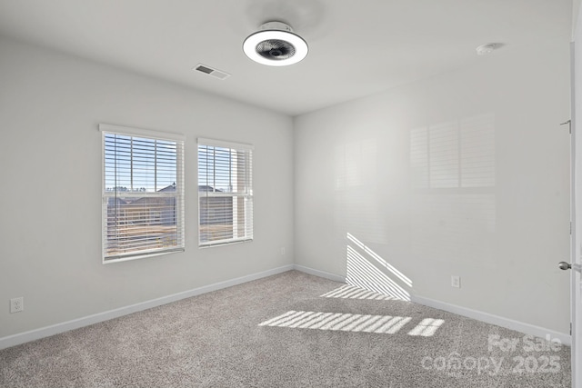 spare room featuring baseboards, visible vents, and light colored carpet