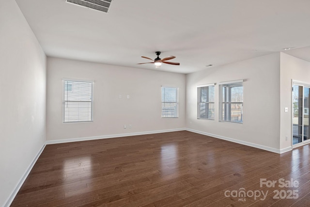 unfurnished room with dark wood-type flooring, visible vents, ceiling fan, and baseboards