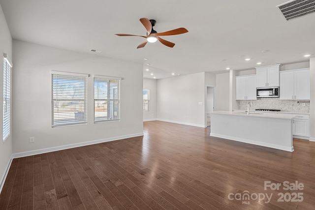 unfurnished living room featuring dark wood-style flooring, recessed lighting, visible vents, a sink, and baseboards