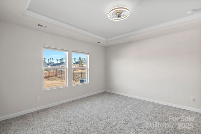 carpeted spare room featuring baseboards, visible vents, and a raised ceiling