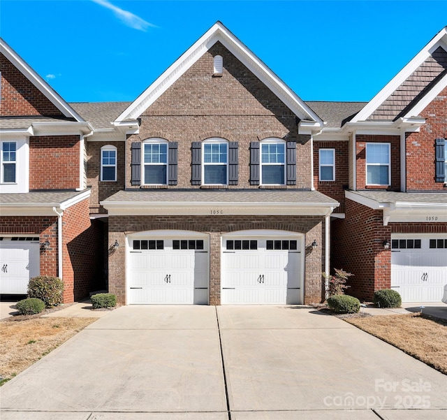 townhome / multi-family property featuring a garage, concrete driveway, brick siding, and a shingled roof