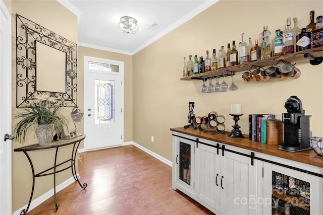 entrance foyer with baseboards, a dry bar, wood finished floors, and crown molding