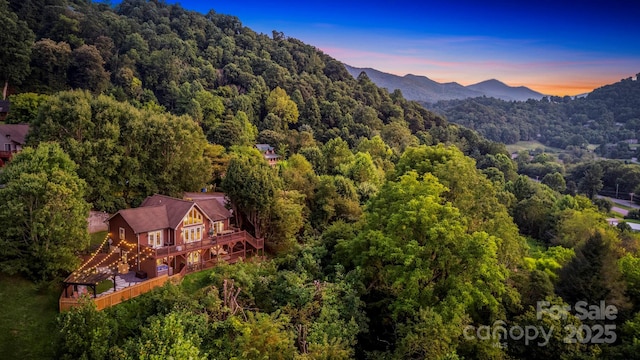 aerial view at dusk featuring a forest view and a mountain view