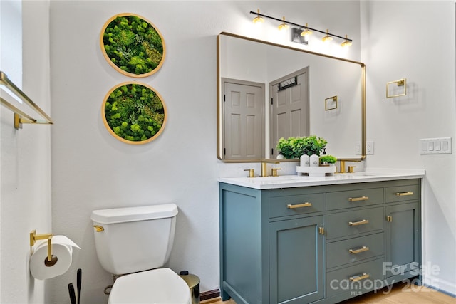 full bath with toilet, double vanity, and a sink