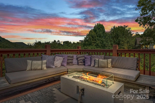 deck at dusk with an outdoor living space with a fire pit