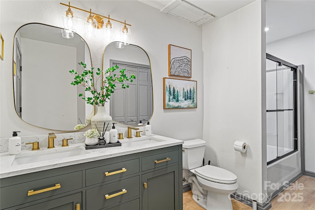 full bath with toilet, double vanity, enclosed tub / shower combo, and a sink