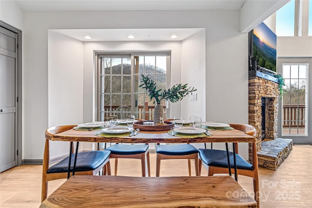 dining room featuring light wood-type flooring, a fireplace, and recessed lighting