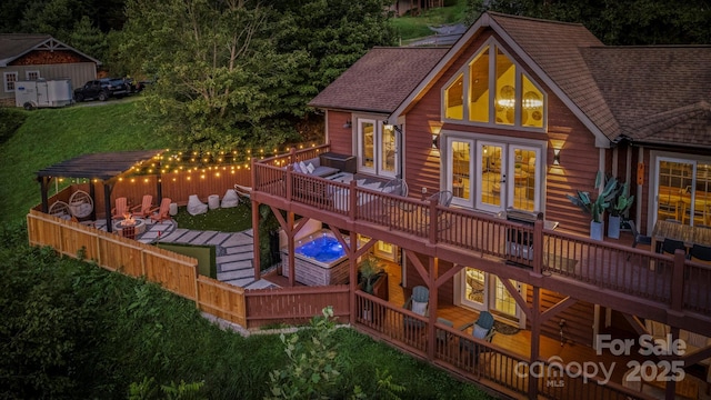 back of property with a shingled roof, a deck, a lawn, and french doors