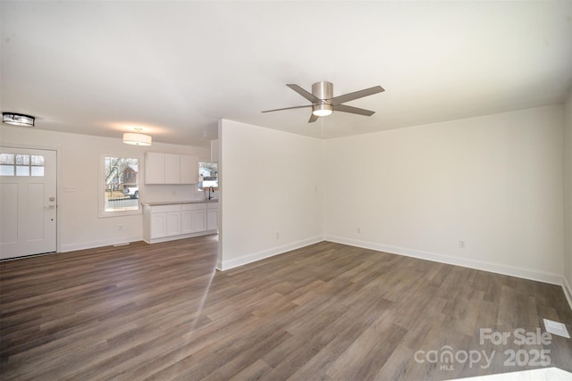 unfurnished living room featuring dark wood-style floors, baseboards, and a ceiling fan