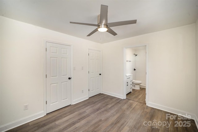 unfurnished bedroom with ceiling fan, dark wood finished floors, baseboards, and ensuite bathroom