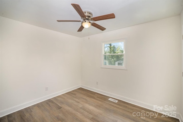 spare room with a ceiling fan, baseboards, visible vents, and wood finished floors