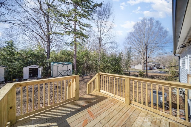 wooden deck with an outbuilding, a shed, and cooling unit