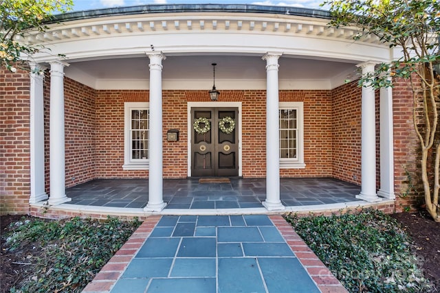 entrance to property with a porch and brick siding