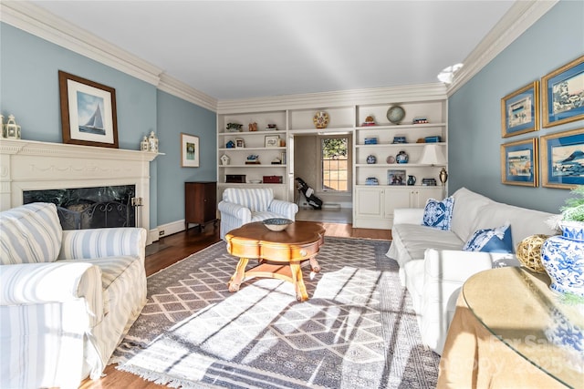 living room with built in shelves, crown molding, a premium fireplace, and wood finished floors