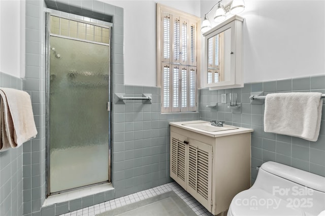 full bathroom with a wainscoted wall, tile walls, toilet, a shower stall, and vanity