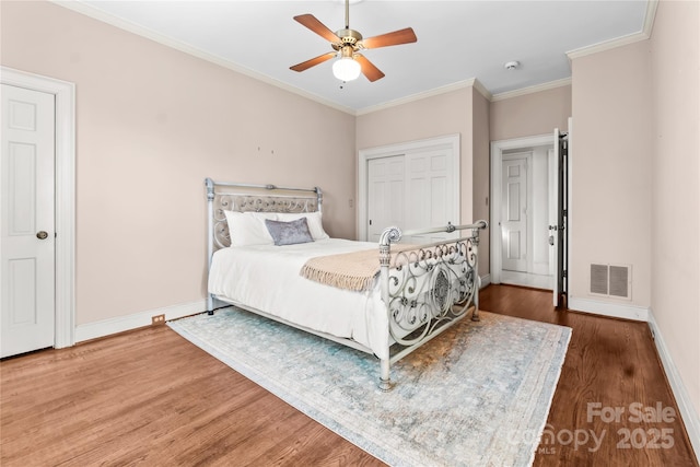 bedroom featuring ornamental molding, visible vents, baseboards, and wood finished floors